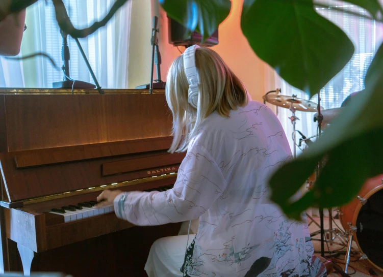 a woman playing a piano in a living room, an album cover, inspired by Elsa Bleda, unsplash, hyperrealism, blonde, billie eilish as a nun, live performance, in a japanese apartment