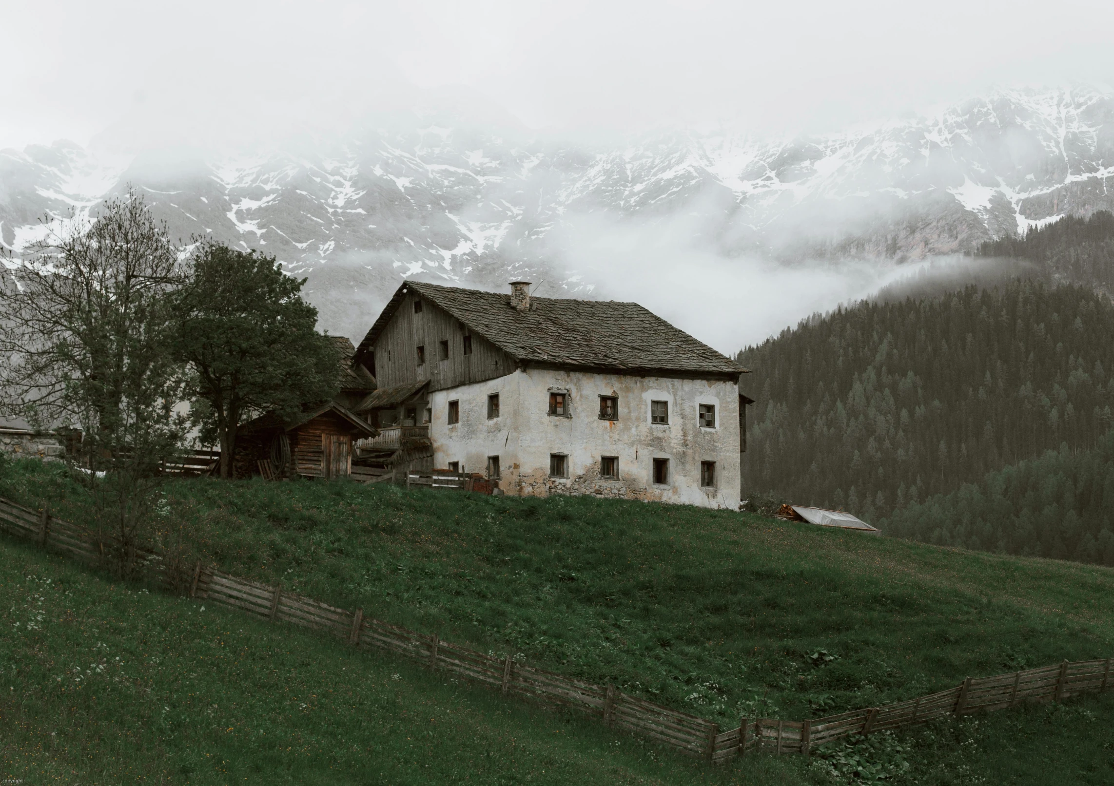 a house sitting on top of a lush green hillside, a black and white photo, inspired by Peter Zumthor, pexels contest winner, renaissance, gloomy colors, barn, moody : : wes anderson, cozy place