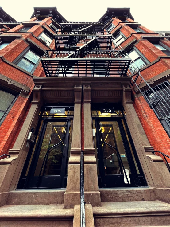 a tall red brick building with lots of windows, a photo, by Bernie D’Andrea, unsplash, harlem renaissance, entrance, profile image, extremely detailed frontal angle, an escape room in a small