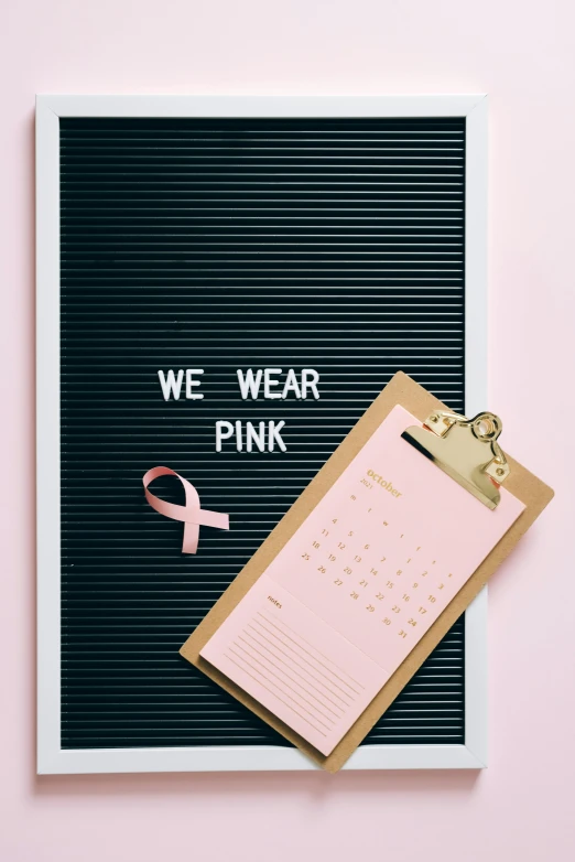 a sign that says we wear pink next to a clipboard with a pink ribbon, a photo, trending on pexels, - 12p, panel, graphic print