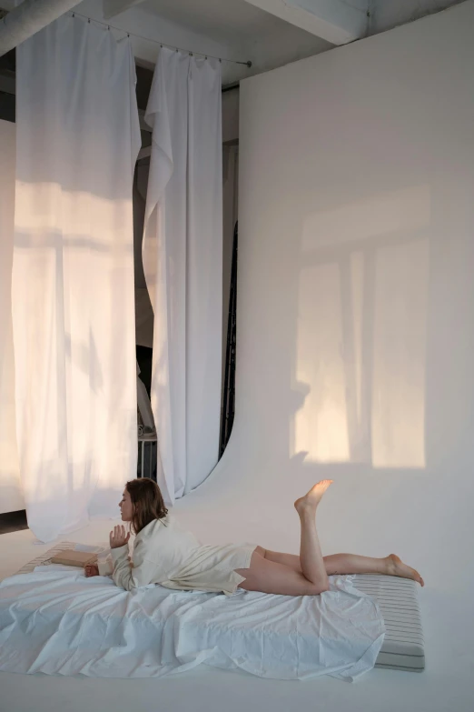 a woman laying on top of a bed next to a window, inspired by Anna Füssli, light and space, studio-lighting, white backdrop, wearing translucent sheet, taken at golden hour