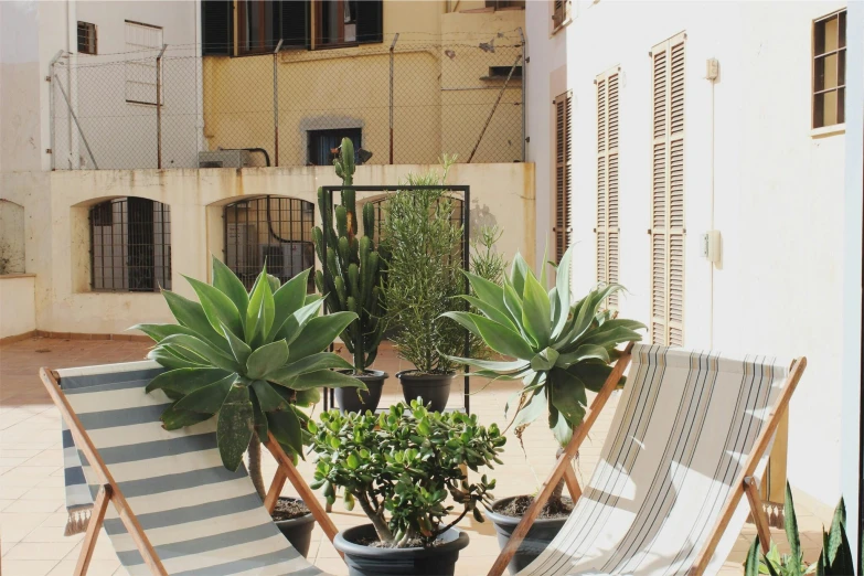 a couple of lawn chairs sitting on top of a patio, inspired by Riad Beyrouti, unsplash, in barcelona, building cover with plant, exterior, conde nast traveler photo