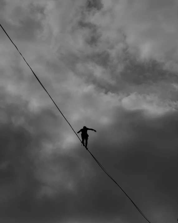 a black and white photo of a person on a tight rope, by Kristian Kreković, unsplash, dramatic sky, ilustration, black & white, electric