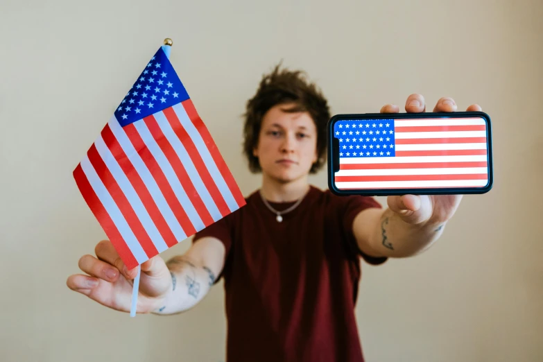 a person holding a cell phone and an american flag, a portrait, pexels, he looks like tye sheridan, american flags, passport photo, 🚀🌈🤩