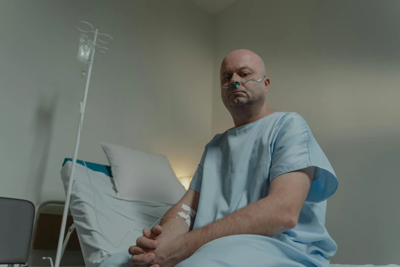 a man in a hospital gown sitting on a hospital bed, a portrait, pexels contest winner, hyperrealism, avatar image, low quality photo, sad expression, colour corrected