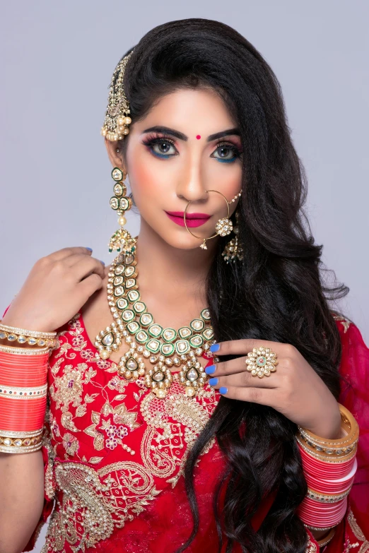 a woman in a red sari posing for the camera, inspired by Saurabh Jethani, wearing gold jewellery, thumbnail, premium, pastel'