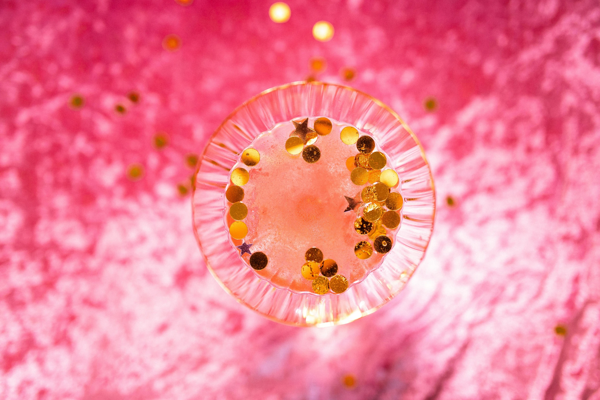 a glass filled with liquid sitting on top of a table, an album cover, by Julia Pishtar, pexels, magic realism, pink and gold color scheme, bubble gum, view from above, disco party