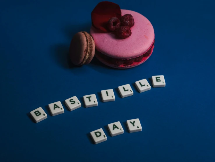a pink macaron sitting on top of a blue table, an album cover, inspired by René Magritte, unsplash contest winner, letterism, d - day, voxels, bravely default inspired, letters