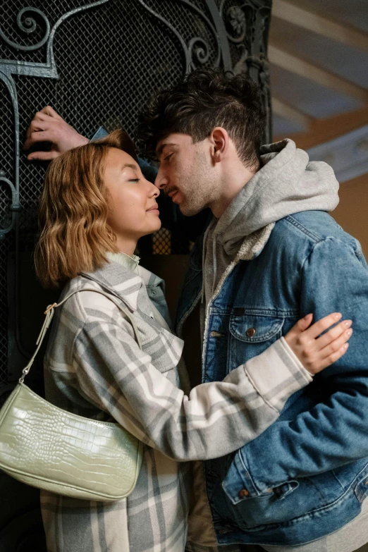 a man and a woman standing next to each other, trending on pexels, photorealism, making out, jean jacket, indoor scene, teenager