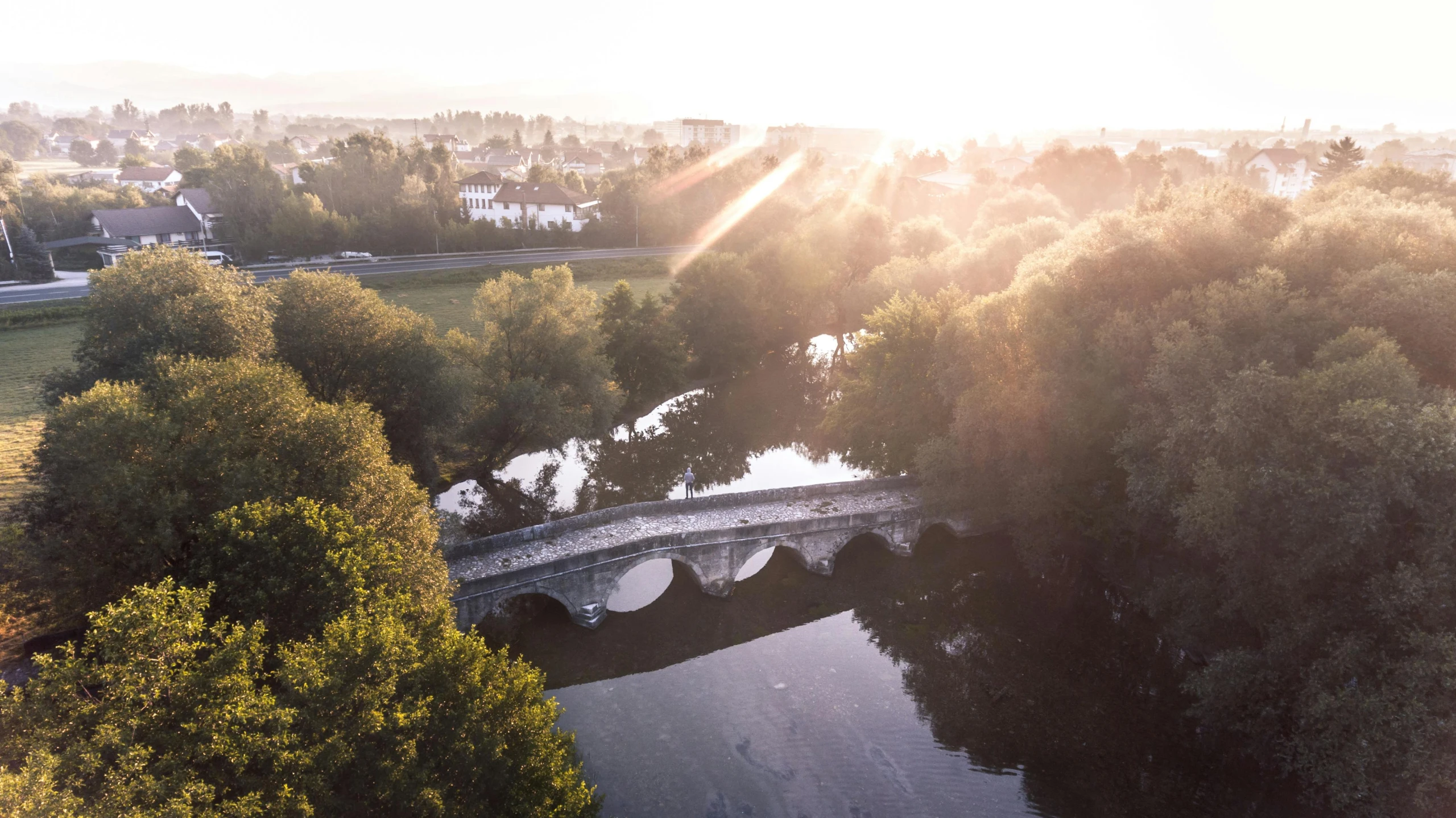 a bridge over a body of water surrounded by trees, a picture, by Tom Bonson, sun lighting from above, normandy, sunrise lighting, pr shoot