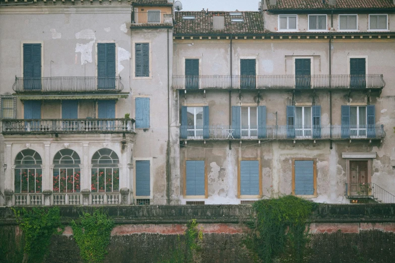 a couple of buildings that are next to each other, an album cover, inspired by Canaletto, pexels contest winner, renaissance, monia merlo, blue and grey, terraced, dirty windows