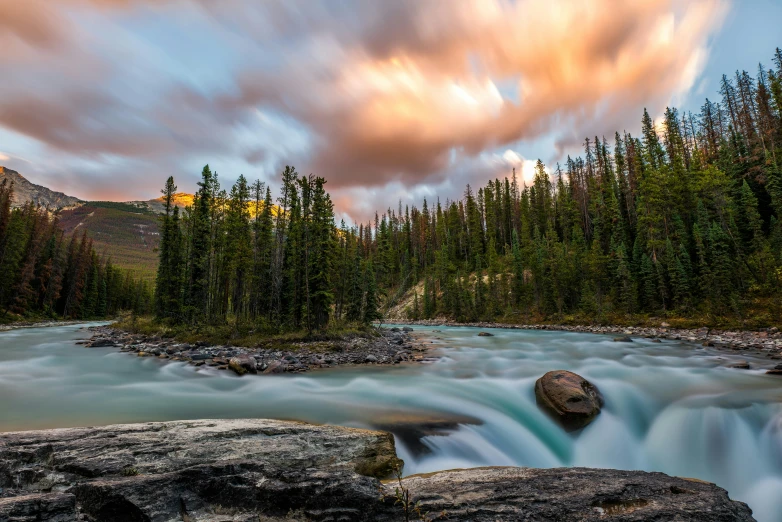 a river flowing through a lush green forest, by Erik Pevernagie, pexels contest winner, banff national park, sunset glow, dramatic skies, white water rapids