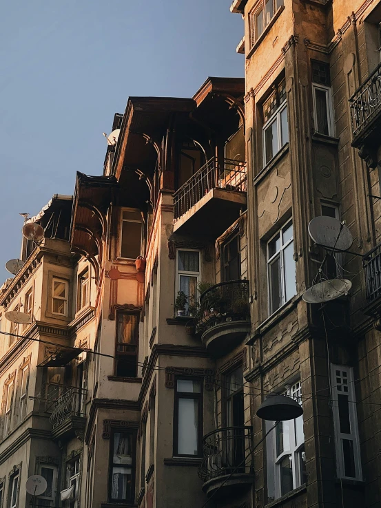 a tall building with lots of windows and balconies, inspired by Niyazi Selimoglu, pexels contest winner, art nouveau, dramatic warm morning light, location of a dark old house, turkish and russian, slide show