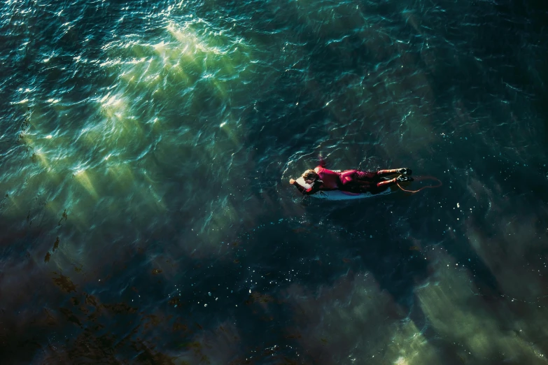 a person laying on a surfboard in the water, inspired by Elsa Bleda, unsplash contest winner, deep colours. ”, crimson, drone photograpghy, ignant