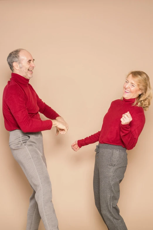 a man and a woman are dancing together, an album cover, by Gavin Hamilton, pexels, antipodeans, red sweater and gray pants, aging, laugh, plain background