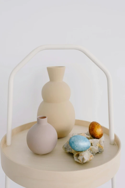 a table with two vases on top of it, an abstract sculpture, unsplash, holding easter eggs, soft muted colors, detailed product image, made of clay