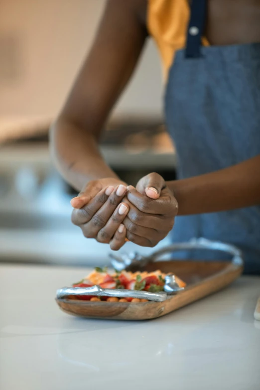 a woman putting toppings on a pizza on a cutting board, pexels contest winner, process art, partially cupping her hands, ethiopian, anatomically correct hands, kitchen counter