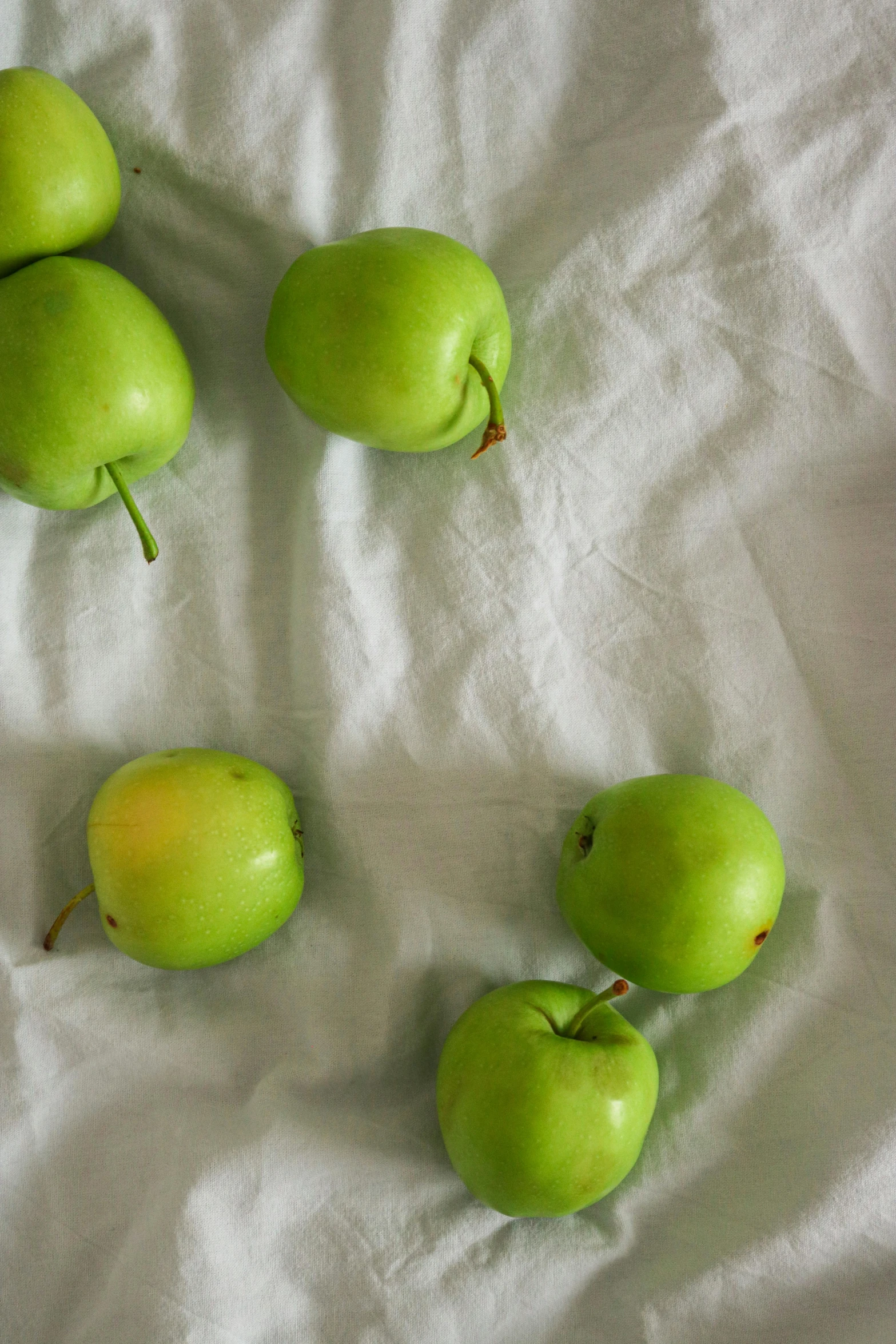 a bunch of green apples sitting on top of a white sheet, a still life, by Jessie Algie, unsplash, 2 5 6 x 2 5 6 pixels, 6 pack, made of glazed, round corners