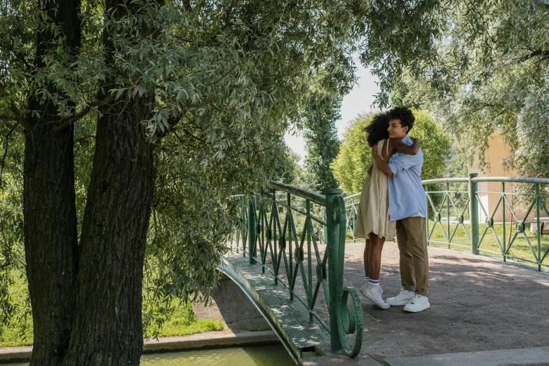 a couple standing next to each other on a bridge, inspired by Enrique Simonet, pexels contest winner, renaissance, willow tree, still from a wes anderson film, hugging, ( ( theatrical ) )