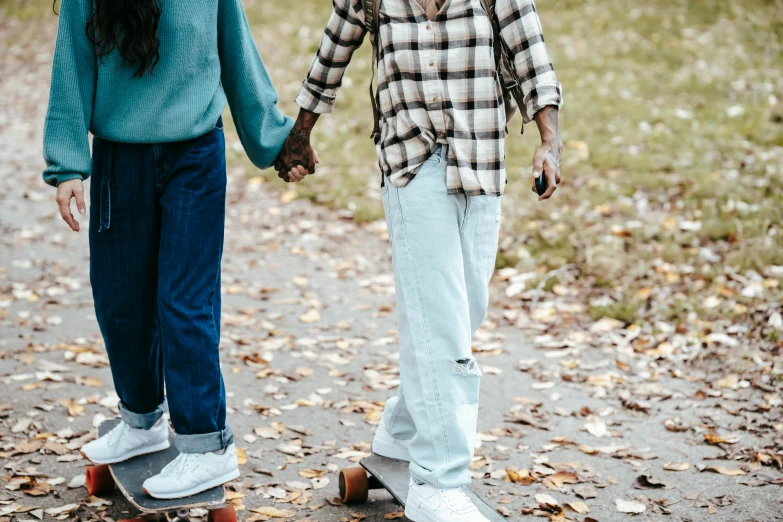 a couple of people that are standing on a skateboard, trending on pexels, holding each other hands, autumnal, wearing denim, sea - green and white clothes