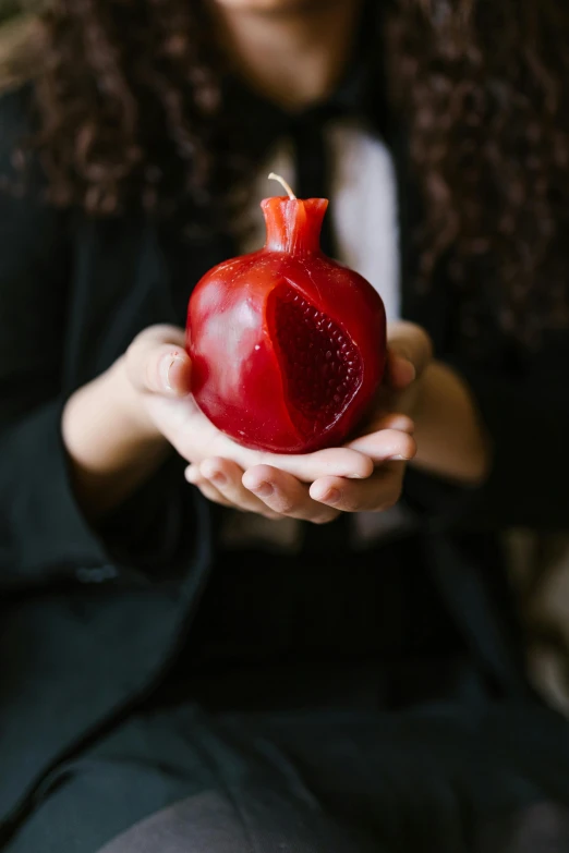 a woman holding a pomegranate in her hands, an album cover, by Julia Pishtar, trending on unsplash, candle wax, 15081959 21121991 01012000 4k, hebrew, 4k polymer clay food photography