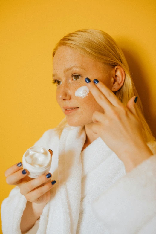 a woman is putting cream on her face, a portrait, trending on pexels, renaissance, white and yellow scheme, blond, product shot, feature