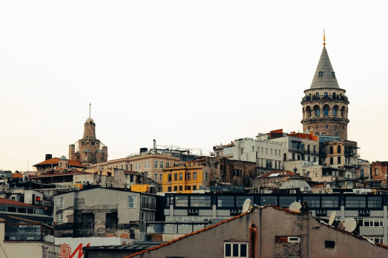 a group of buildings with a clock tower in the background, a photo, pexels contest winner, art nouveau, turkey, view from a distance, grayish, panoramic