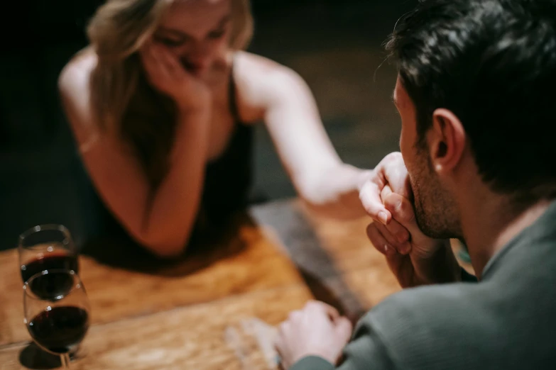 a man and a woman sitting at a table, pexels contest winner, intense flirting, on a rough wooden dungeon table, zoomed in, sydney hanson