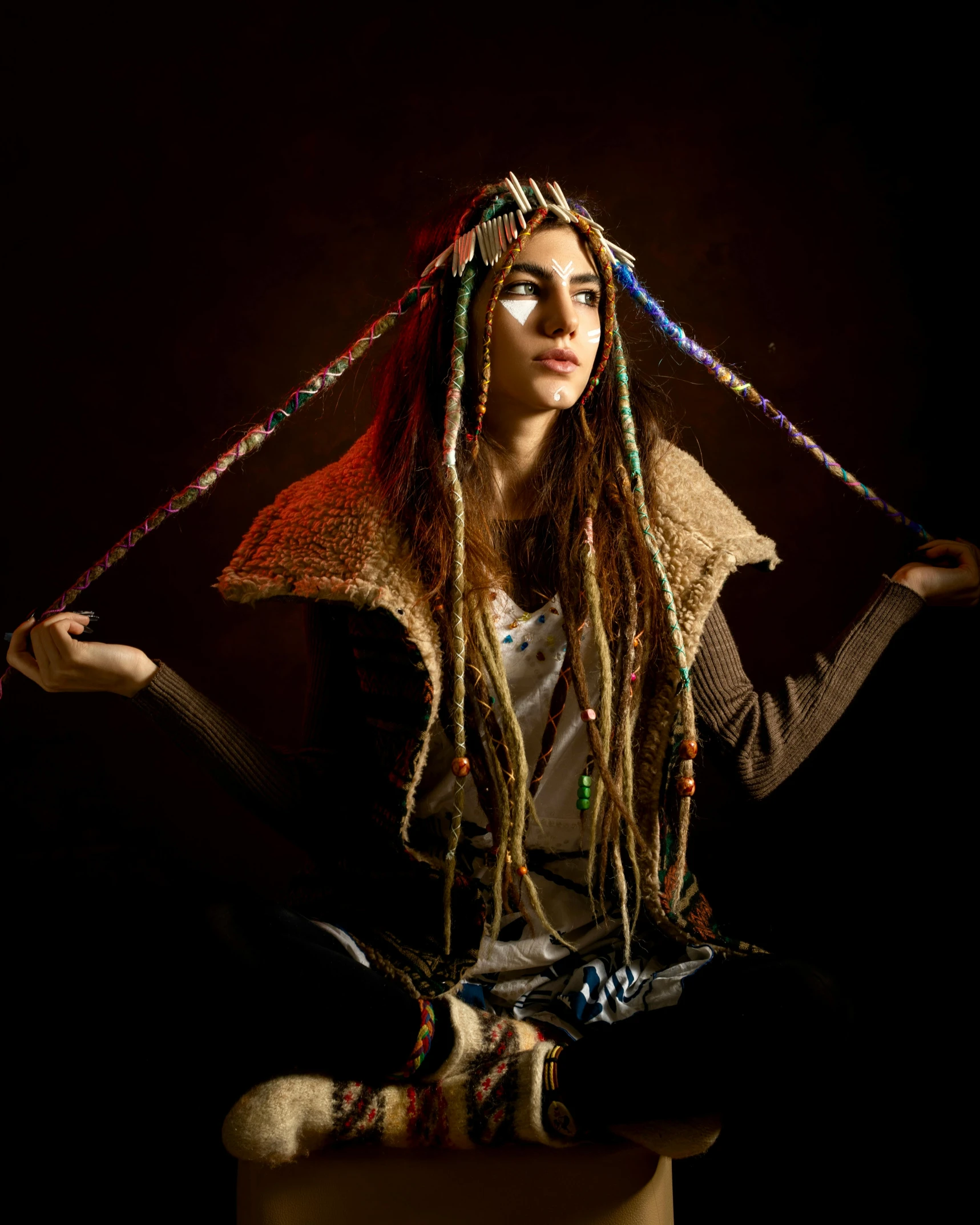 a woman with dreadlocks sitting on a stool, inspired by Leonardo da Vinci, unsplash, she is dressed in shaman clothes, fiber optic hair, still of rainbow ophanim, scarf made from spaghetti