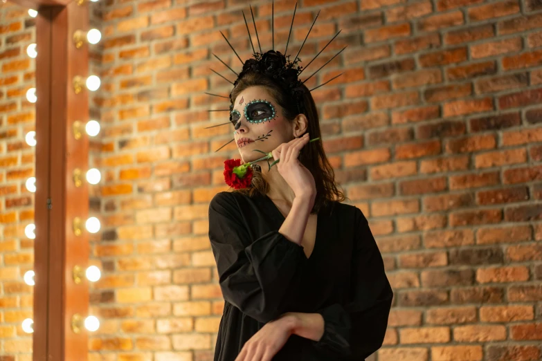 a woman standing in front of a brick wall, inspired by Frida Kahlo, pexels contest winner, gothic art, tibetan skeleton dancer, black makeup, headpiece headpiece headpiece, 1614572159