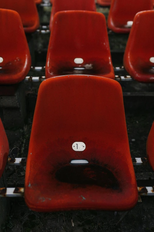 a group of red chairs sitting next to each other, happening, football, deteriorated, alessio albi, still photograph