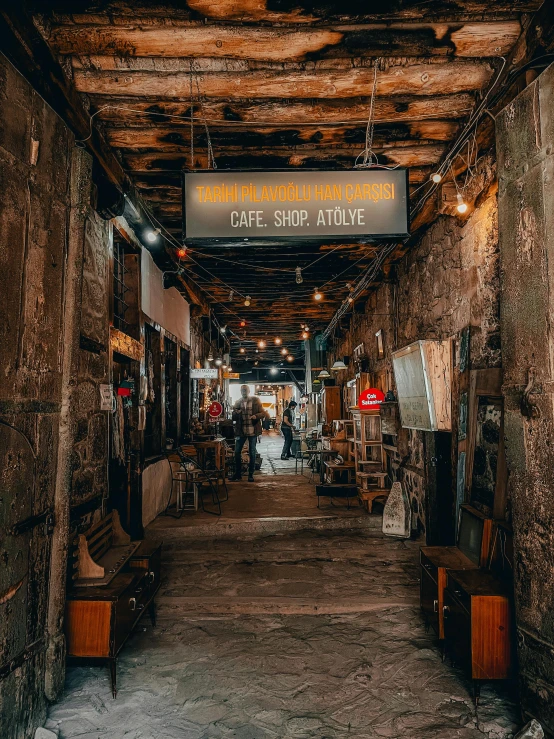 the inside of a building with a sign hanging from the ceiling, pexels contest winner, old jeddah city alley, cafe lighting, stone grotto in the center, new york back street