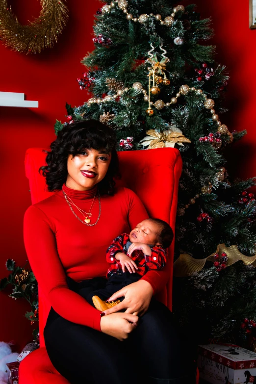 a woman sitting in a red chair holding a baby, shutterstock contest winner, wearing festive clothing, zendaya, mixed race, plus size