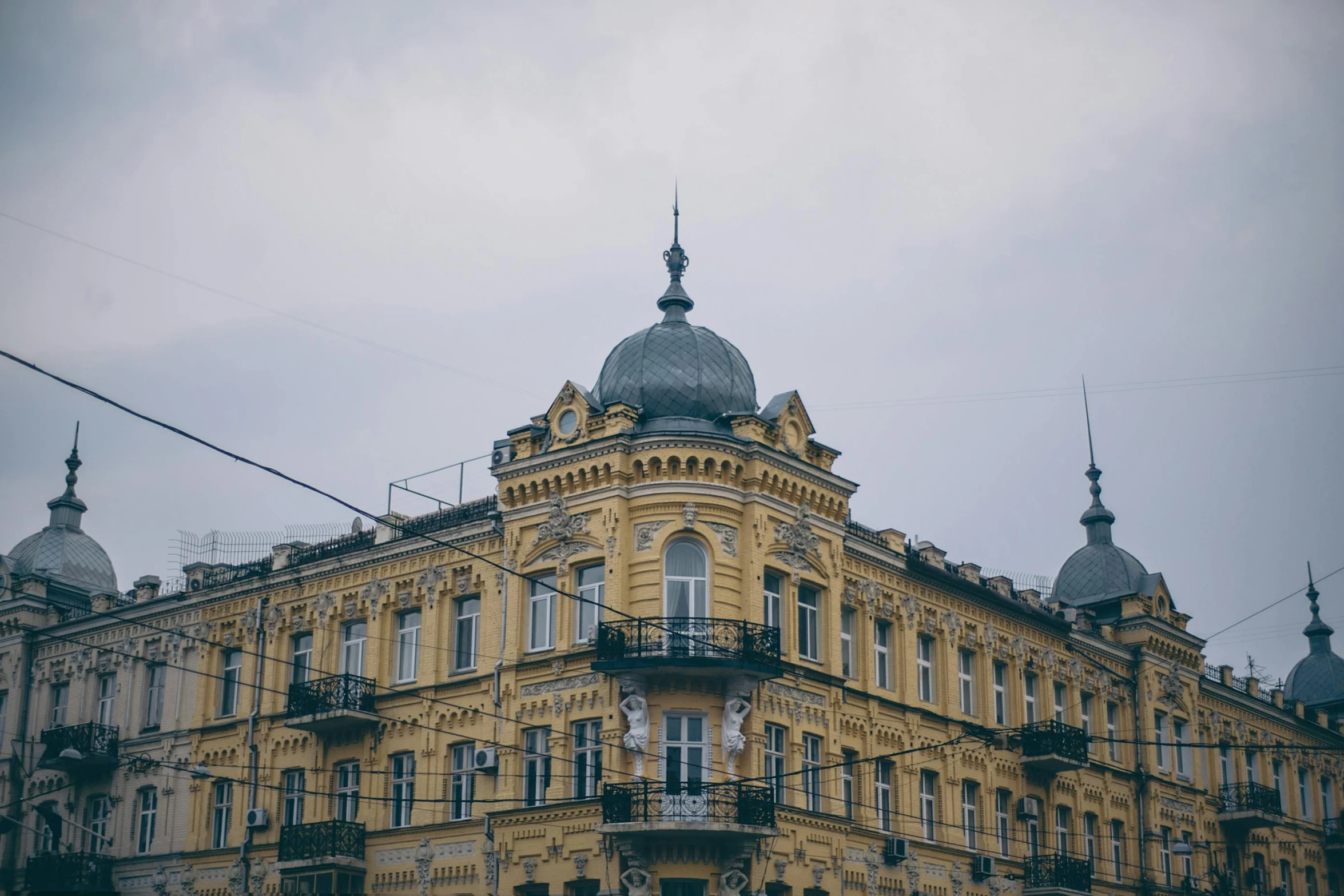 a large yellow building with many windows and balconies, by Emma Andijewska, pexels contest winner, art nouveau, overcast skies, ukraine. professional photo, square, dressed in ornate