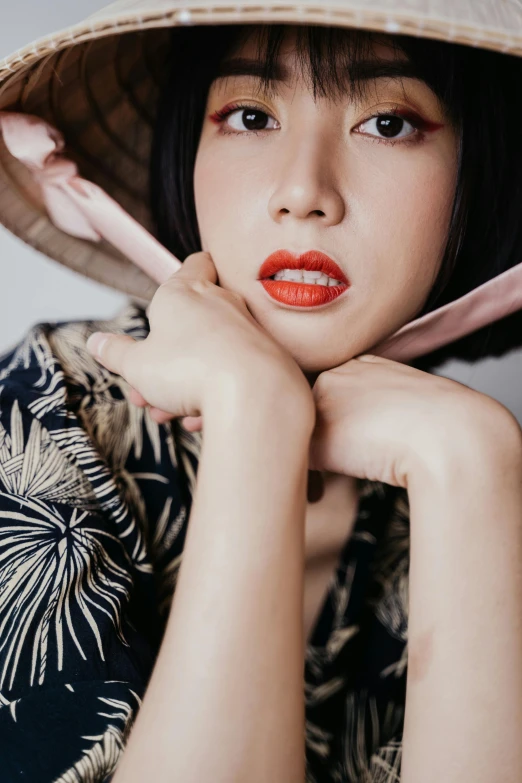 a close up of a person wearing a hat, a colorized photo, inspired by Ina Wong, trending on pexels, coral lipstick, beautiful asian woman sitting, square, ilustration