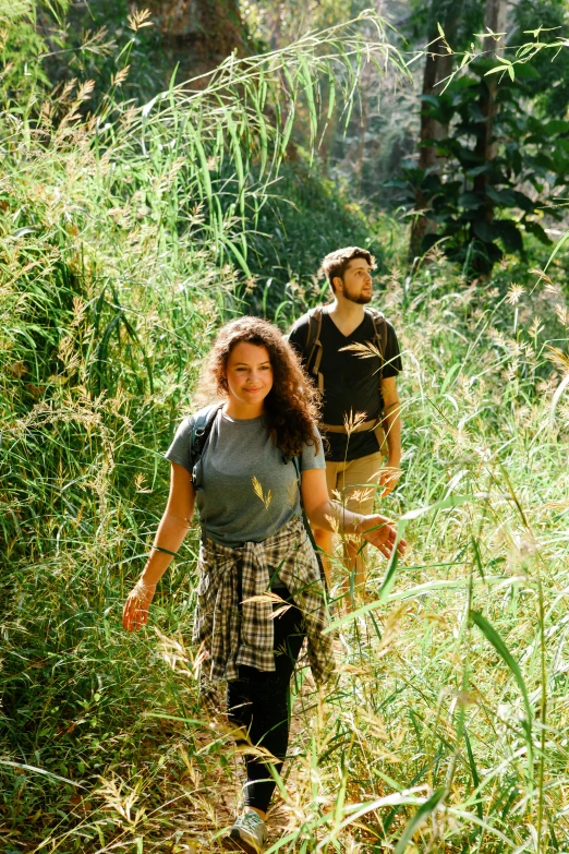 a couple of people that are walking in the grass, in a jungle, looking towards camera, trecking, profile image