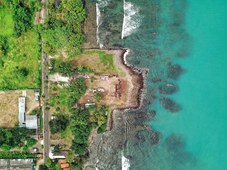 a large body of water next to a lush green hillside, an album cover, pexels contest winner, hurufiyya, ruined subdivision houses, sri lanka, view from above on seascape, thumbnail