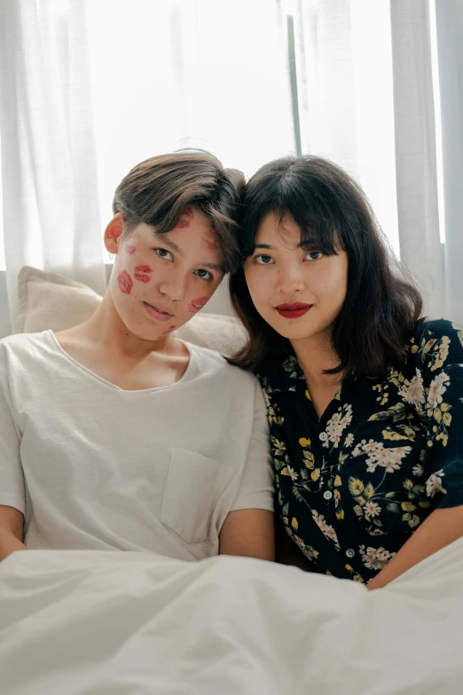 a woman sitting next to a man on a bed, by Juliette Leong, facial scar, lovingly looking at camera, taejune kim, lgbtq