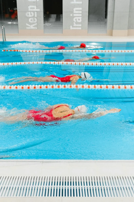 a group of people swimming in a pool, fast paced, head down, panels, head straight down