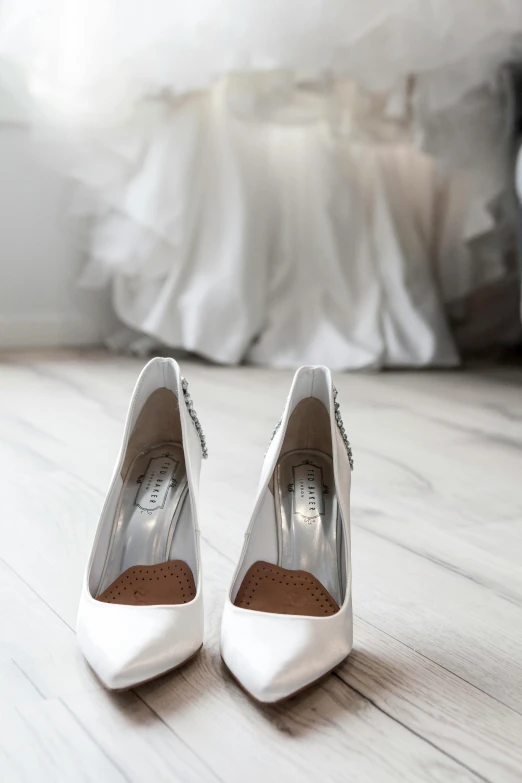 a pair of white shoes sitting on top of a wooden floor, white gown, silver details, standing in corner of room, peter marlow photography