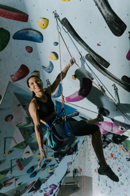 a woman climbing up the side of a rock wall, happening, things hanging from ceiling, posed, vault, manuka