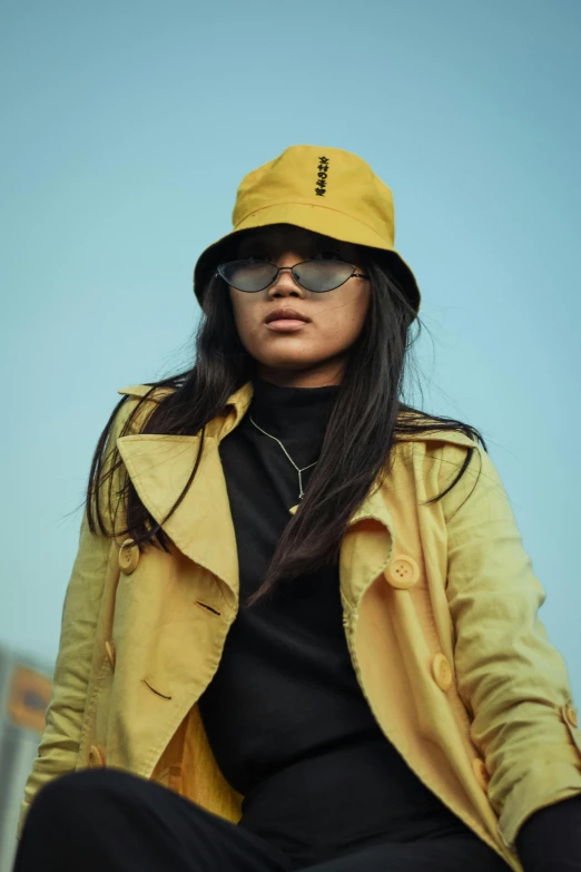 a woman wearing a yellow hat and jacket, inspired by Zhu Da, trending on pexels, pyramid hoodvisor, female with long black hair, student, shades