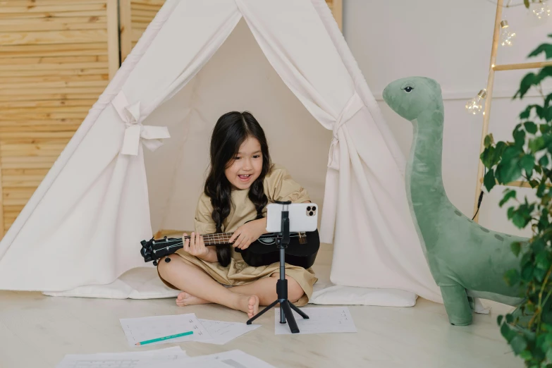 a little girl sitting on the floor playing a guitar, inspired by Abidin Dino, pexels contest winner, standing microphones, teepee, miniature product photo, claymation character