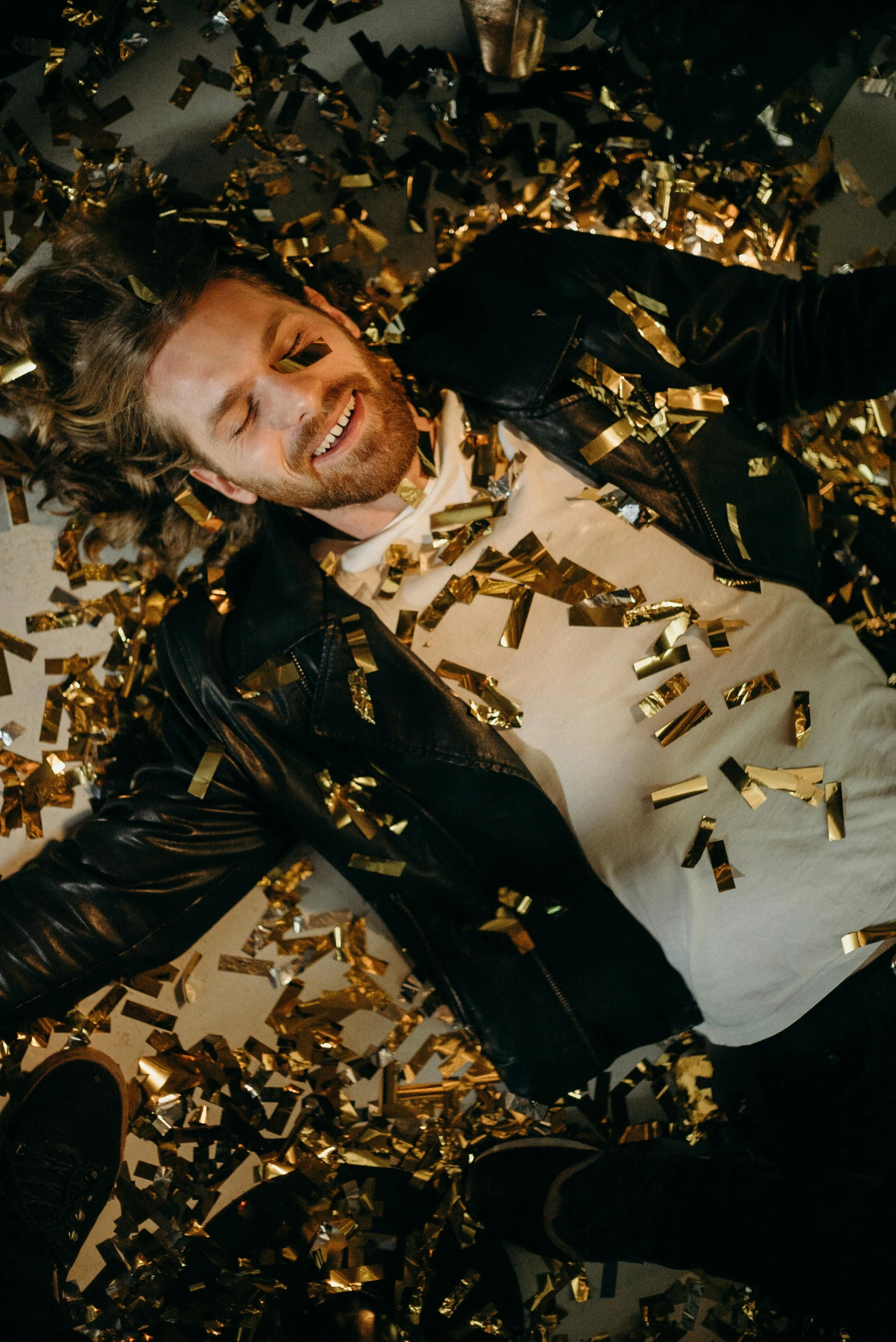 a man laying on the ground surrounded by confetti, inspired by James Morrison, happening, gold hair, felix englund, gold metal, looking happy