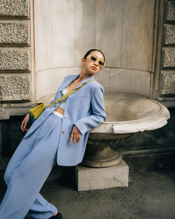 a woman in a blue suit leaning against a wall, inspired by Giambattista Pittoni, trending on pexels, bauhaus, wearing versace sunglasses, thumbnail, pastel, lulu chen