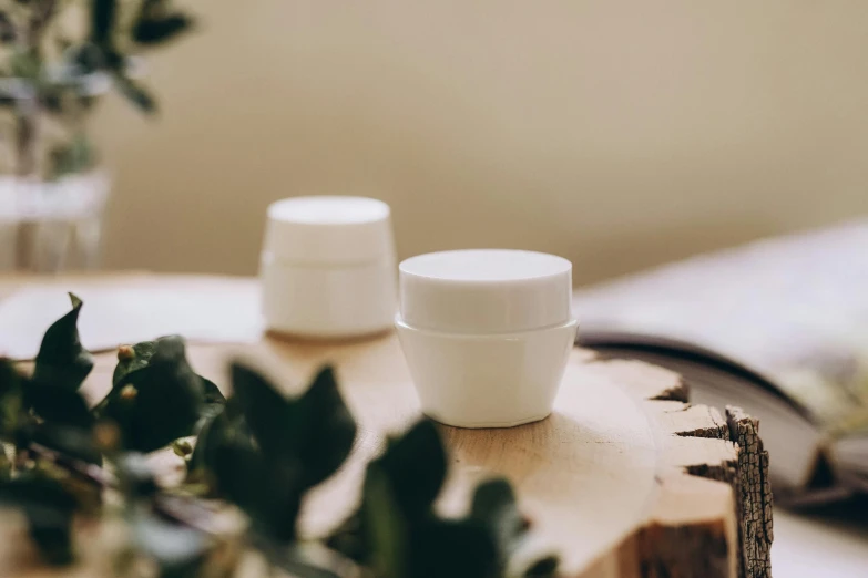 a couple of jars sitting on top of a wooden table, trending on pexels, ivory make up, silicone cover, 35 mm product photo”, white