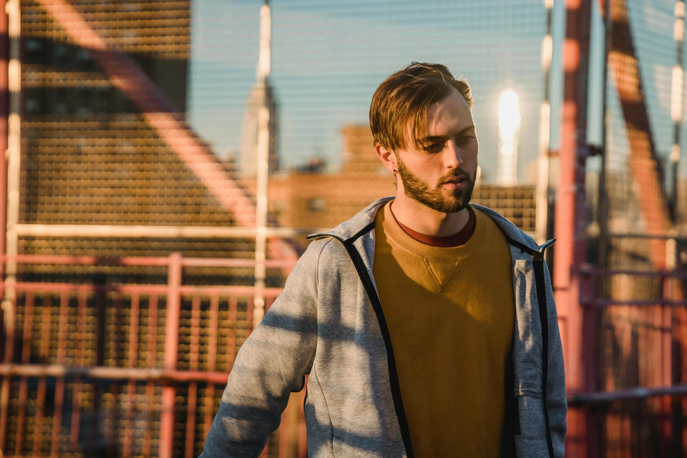 a man walking across a bridge holding a skateboard, a portrait, pexels contest winner, wearing a yellow hoodie, charlie cox, brooklyn background, looking serious