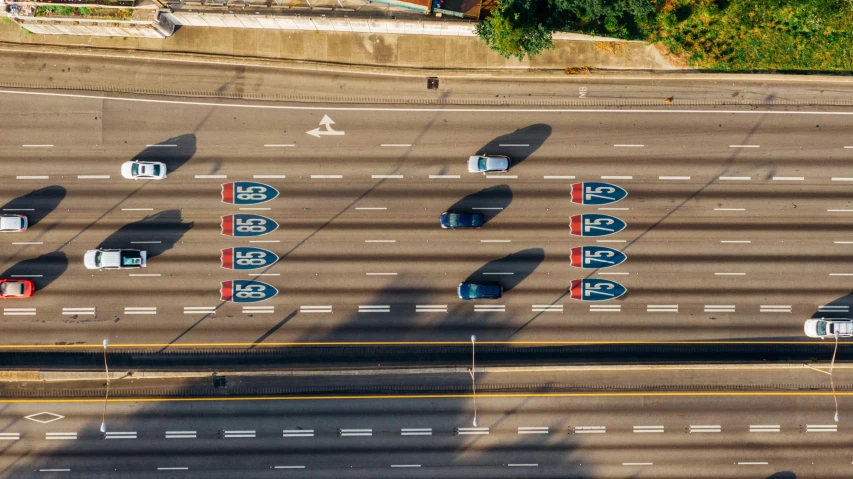 a highway filled with lots of cars driving down it, by Jeffrey Smith, pexels contest winner, graffiti, long shadow, symmetrical composition, memphis, topdown