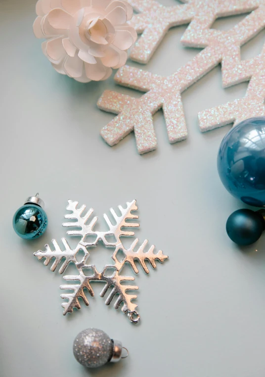 a couple of snowflakes sitting on top of a table, blue and grey theme, various items, promo image, pearlescent