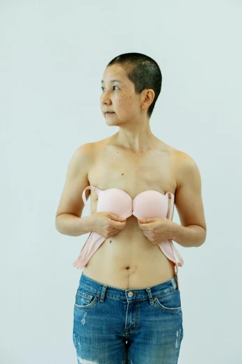 a woman standing in front of a white wall, inspired by Zhang Kechun, unsplash, posing together in bra, emaciated shaved face, yoshikata amano, rinko kawauchi